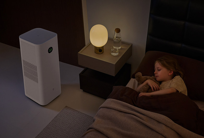 Mijia Smart Air Purifier 6 Plus obok łóżka w sypialni ze śpiącą osobą