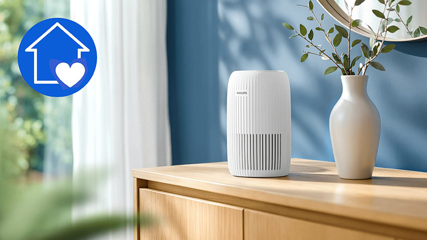 Biały Philips AC0520/10 na drewnianej komodzie obok wazonu