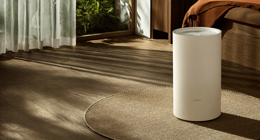 Xiaomi Smart Dehumidifier Lite na okrągłym dywanie przy oknie w nasłonecznionym wnętrzu