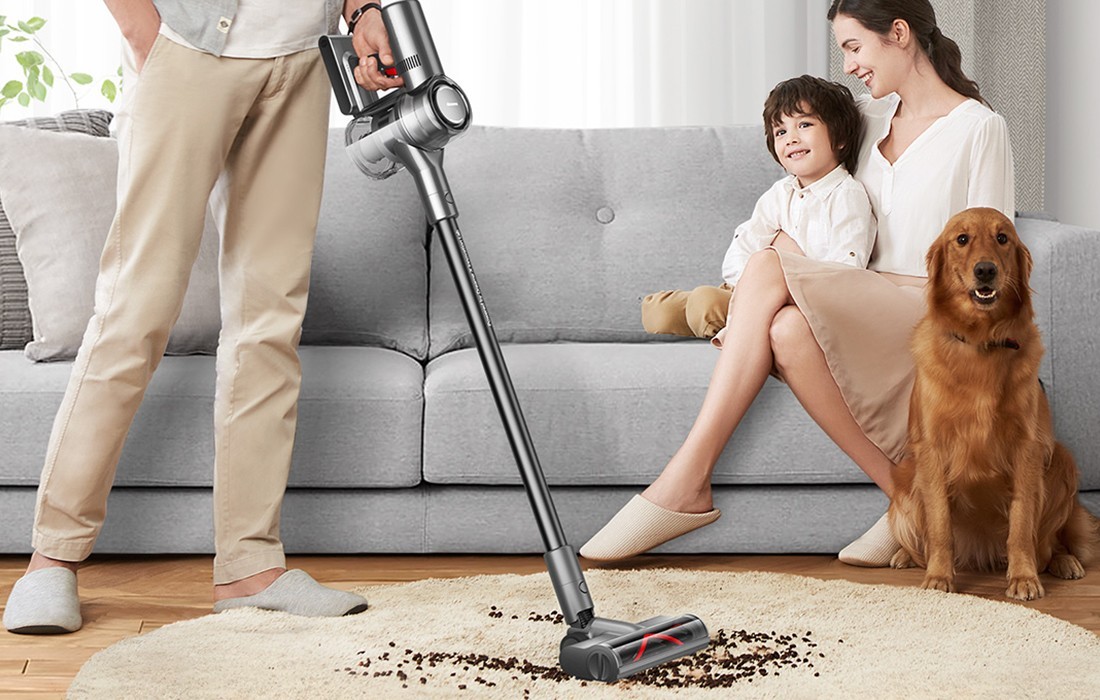 Mężczyzna odkurza dywan w obecności syna, żony i psa