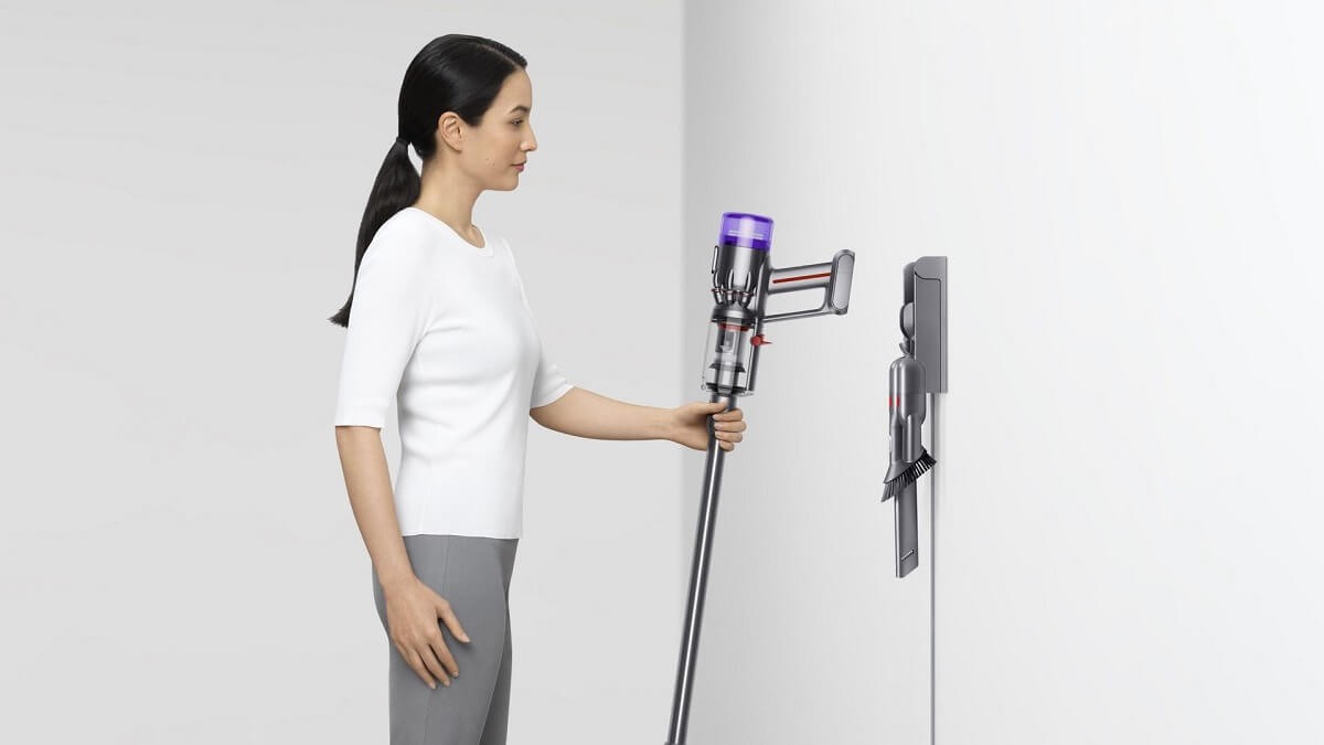 Kobieta odwieszająca odkurzacz Dyson do stacji dokującej